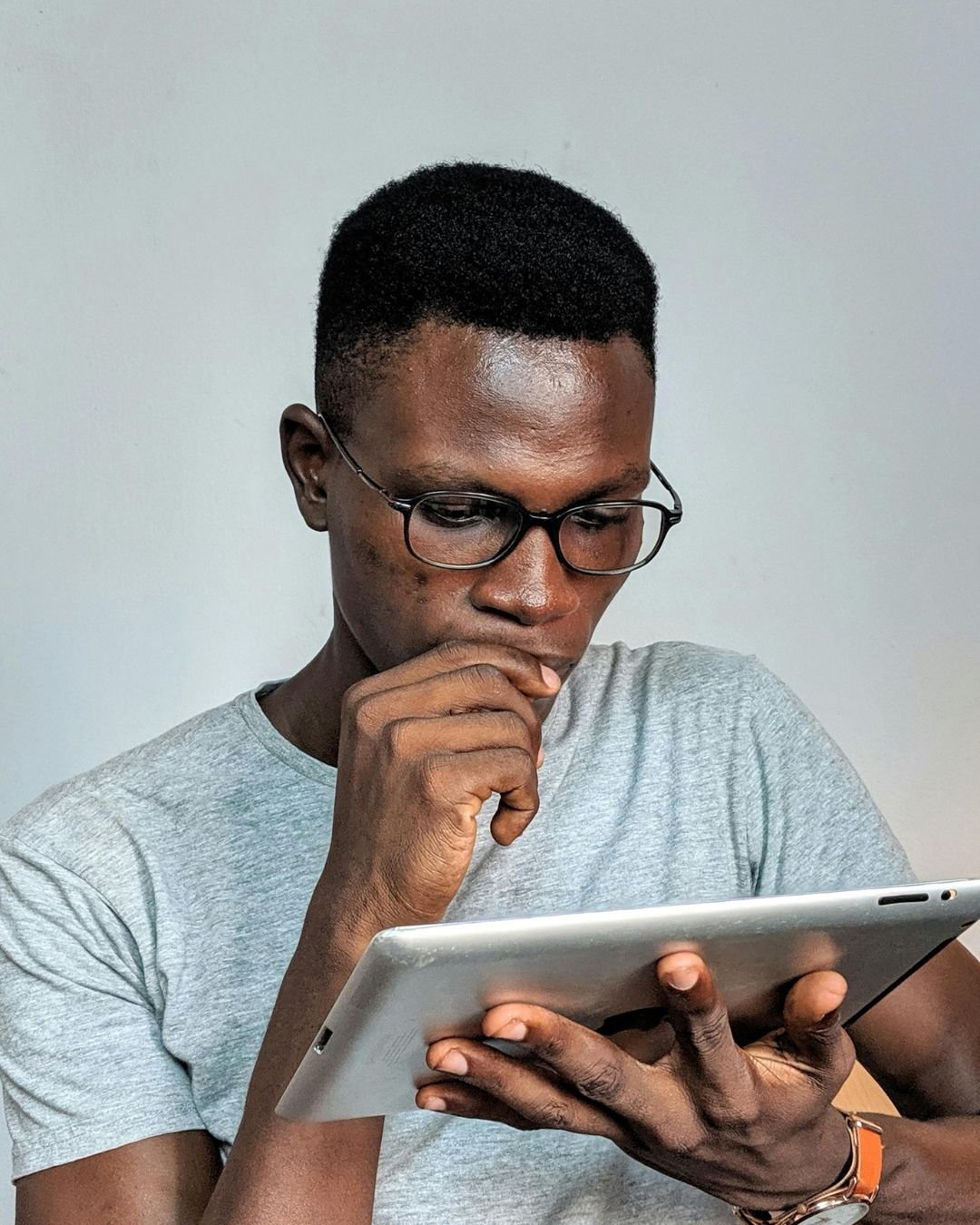 A thoughtful man in glasses looking at a tablet, symbolizing business owners researching why their business isn’t showing up online.