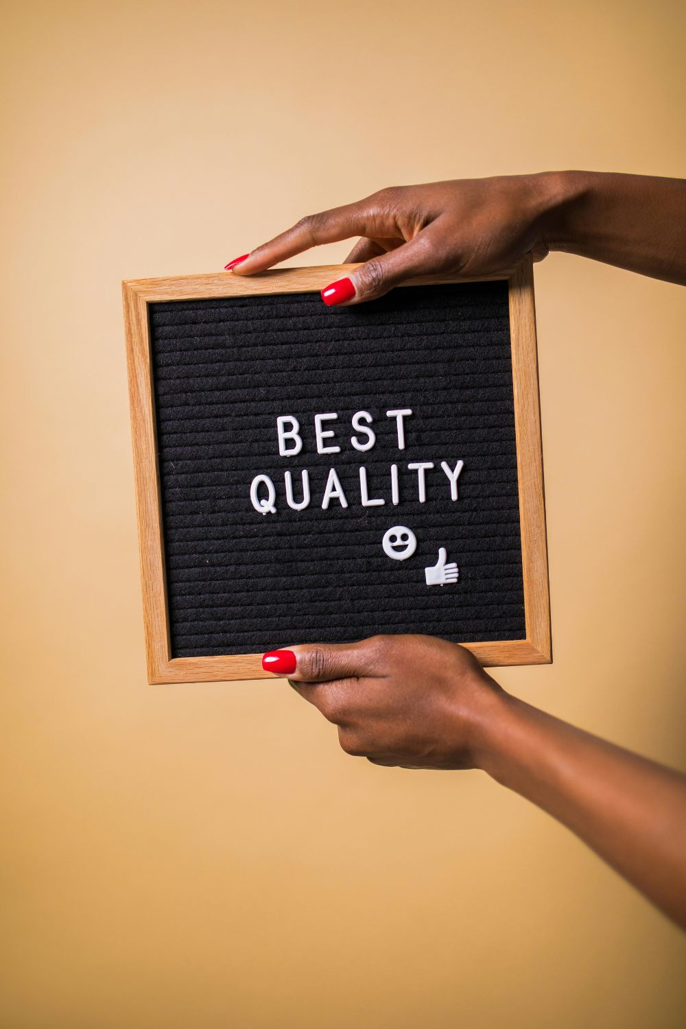 Hands holding a wooden frame with black felt board showing the words “Best Quality” — symbolizing the best social media apps in 2025.