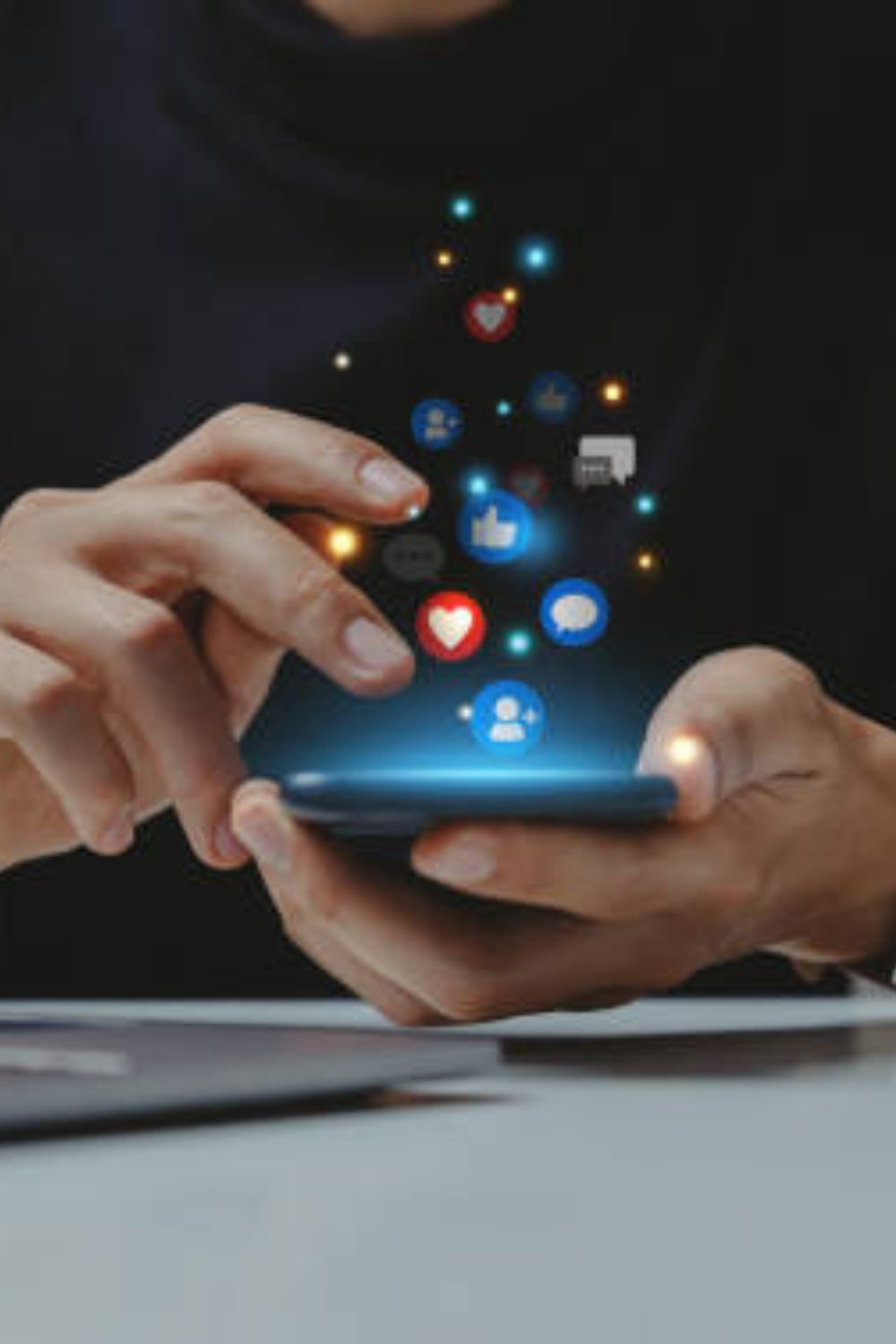 Close-up of hands using a smartphone with floating social media icons for likes, comments, and shares.