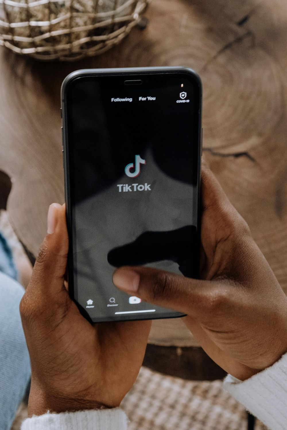 Person holding a smartphone with the TikTok app open, ready to create or watch short-form video content.