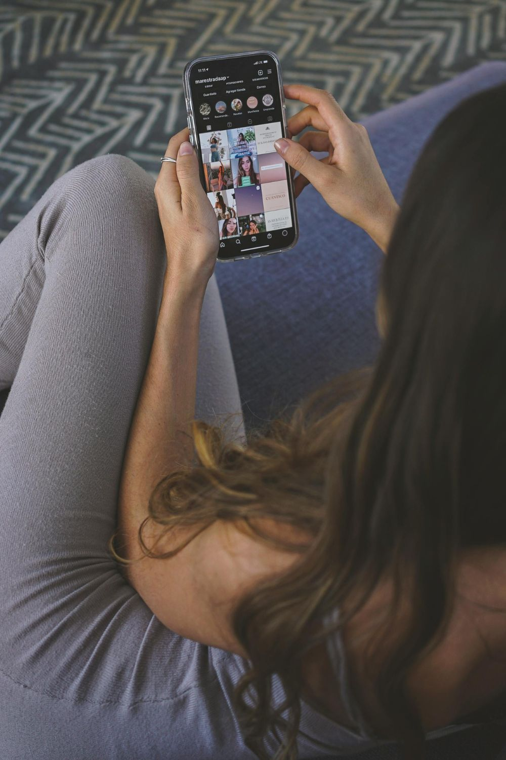 Woman holding a smartphone while scrolling through Instagram feed, representing future social media use in 2030.