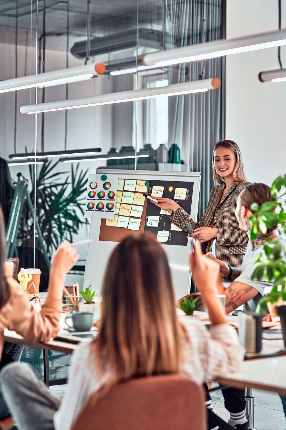 Business team discussing a social media campaign timeline during a presentation with sticky notes on a whiteboard.