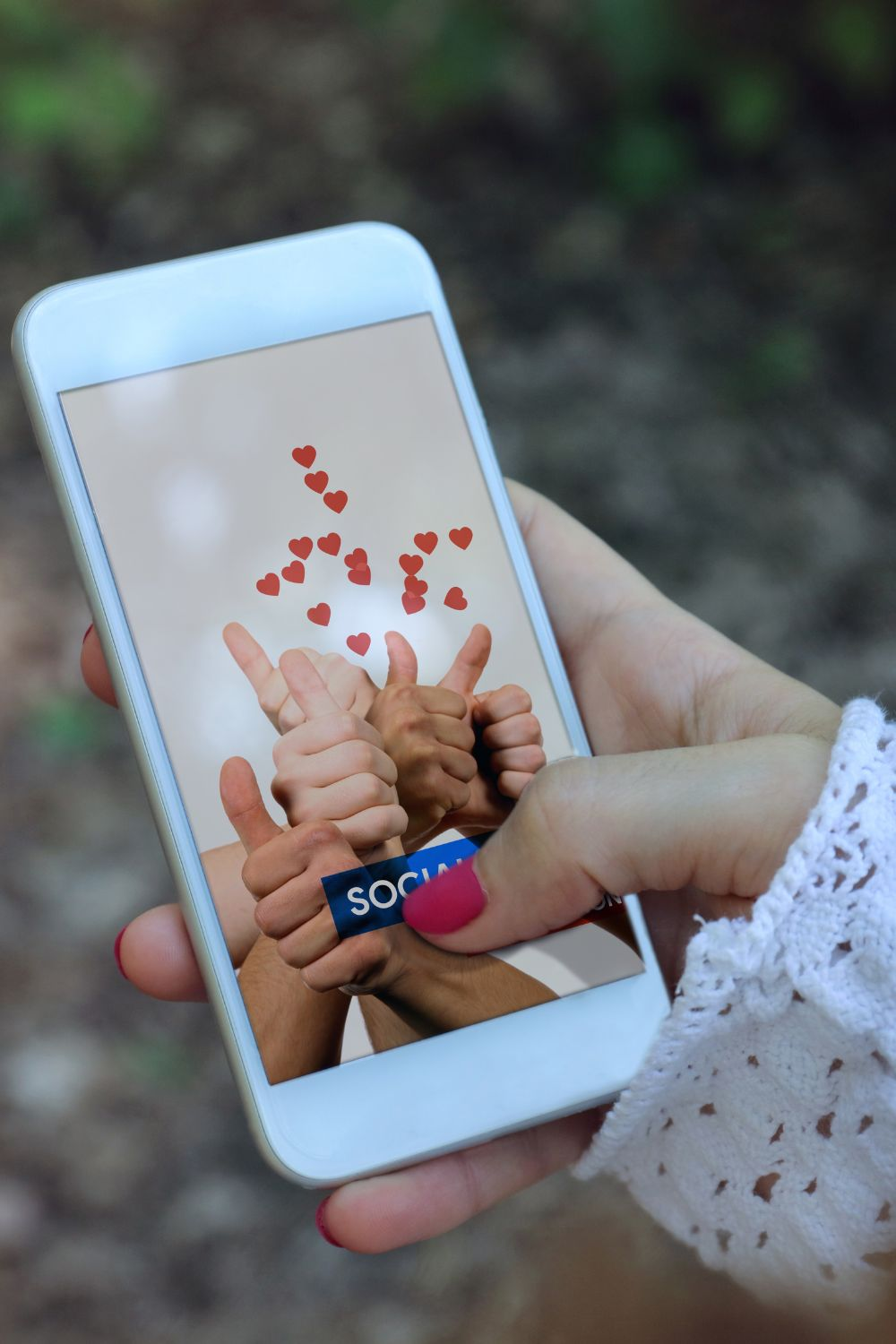 Person holding smartphone showing social media likes and thumbs up with floating heart icons.