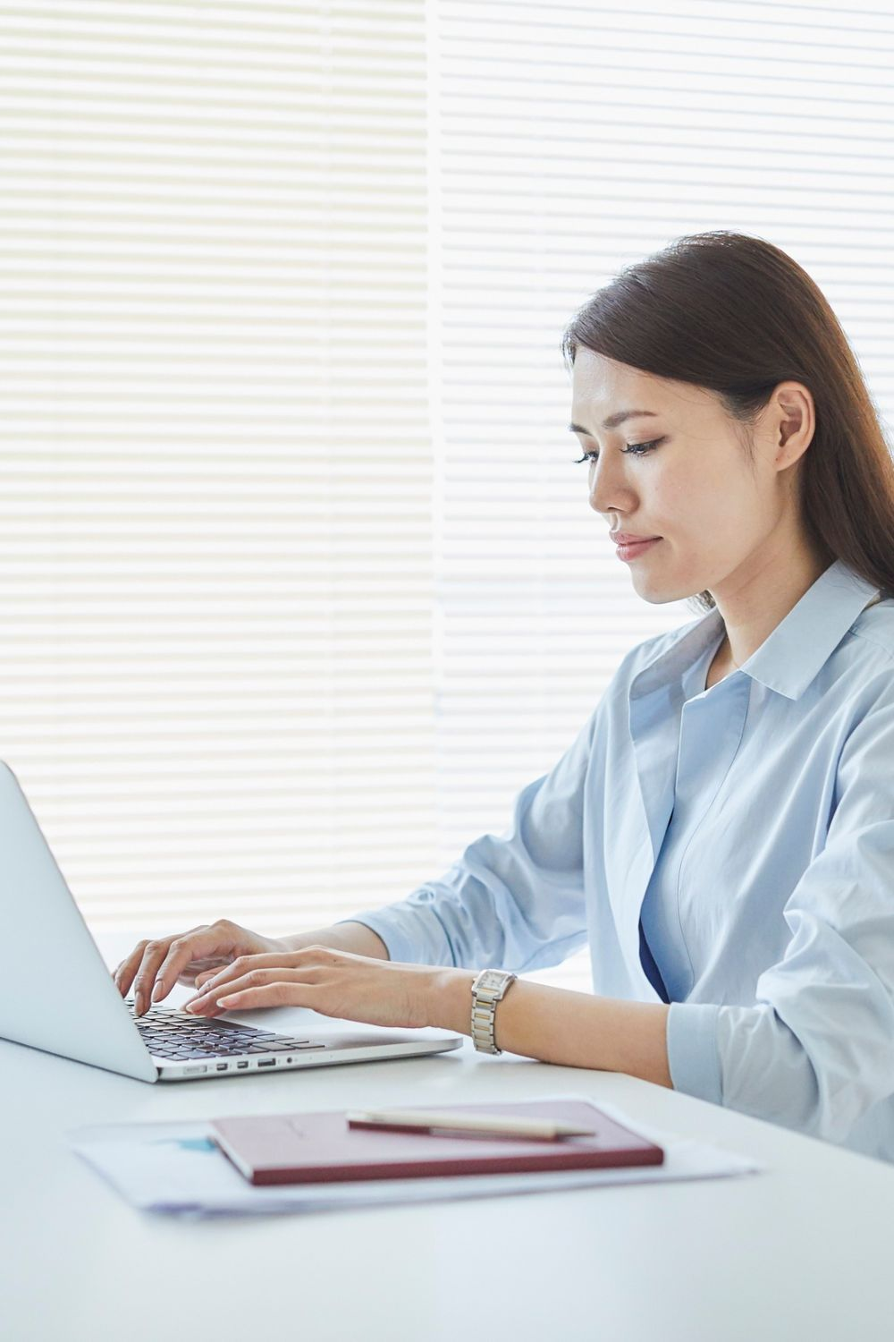 Businesswoman typing on a laptop at a desk, focusing on digital marketing strategy.