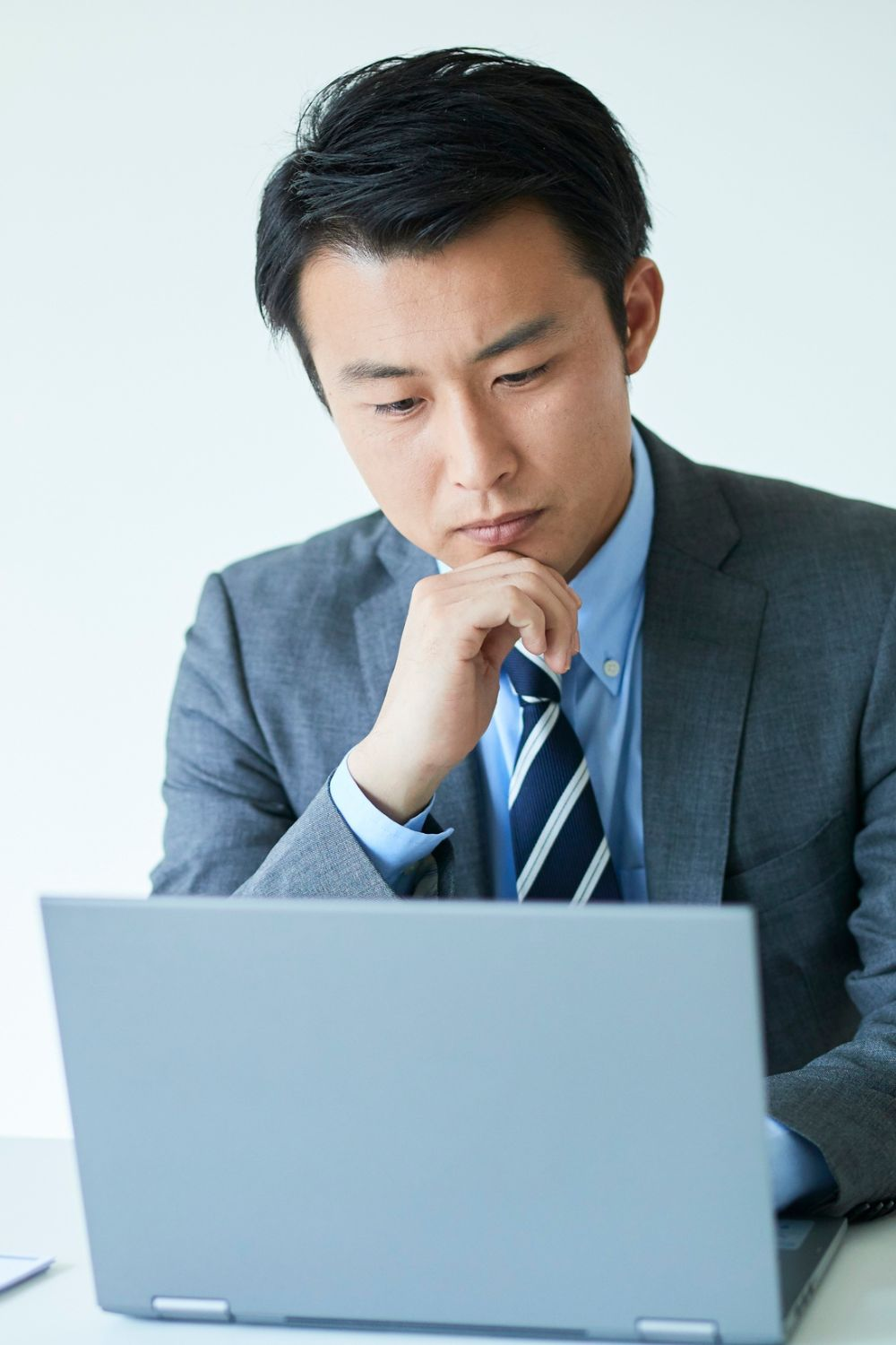 Business professional in a suit focusing on laptop work at a desk.
