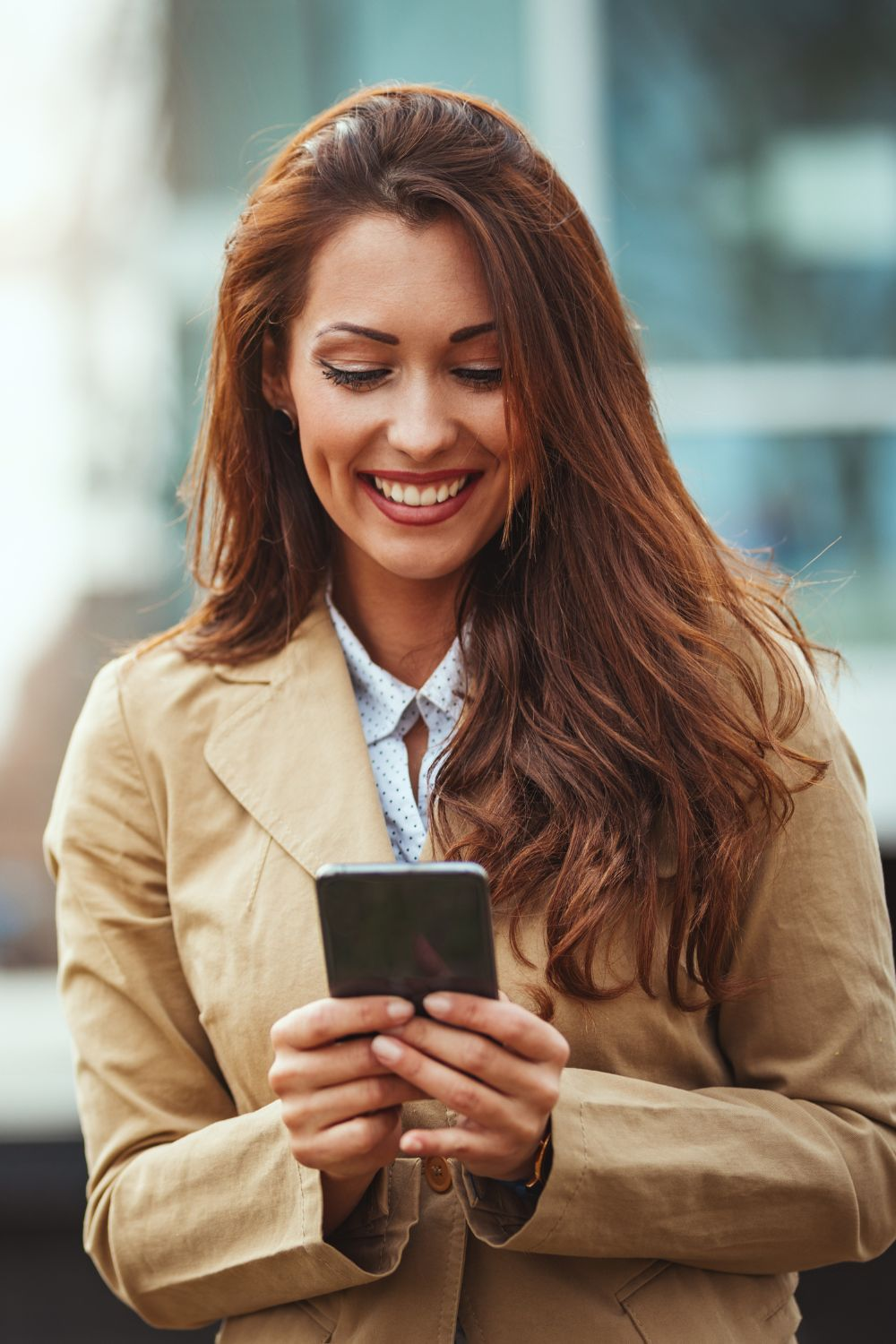 Smiling woman using a smartphone outdoors, engaging with social media.