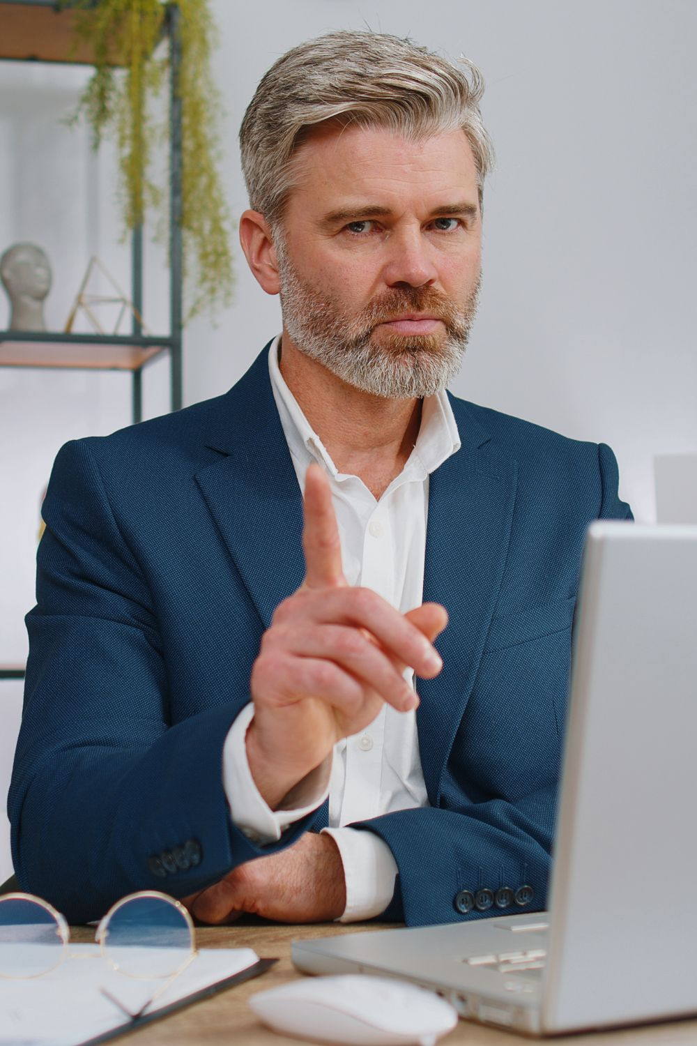 Business professional in a suit pointing a finger while working on a laptop, emphasizing common social media campaign mistakes to avoid.
