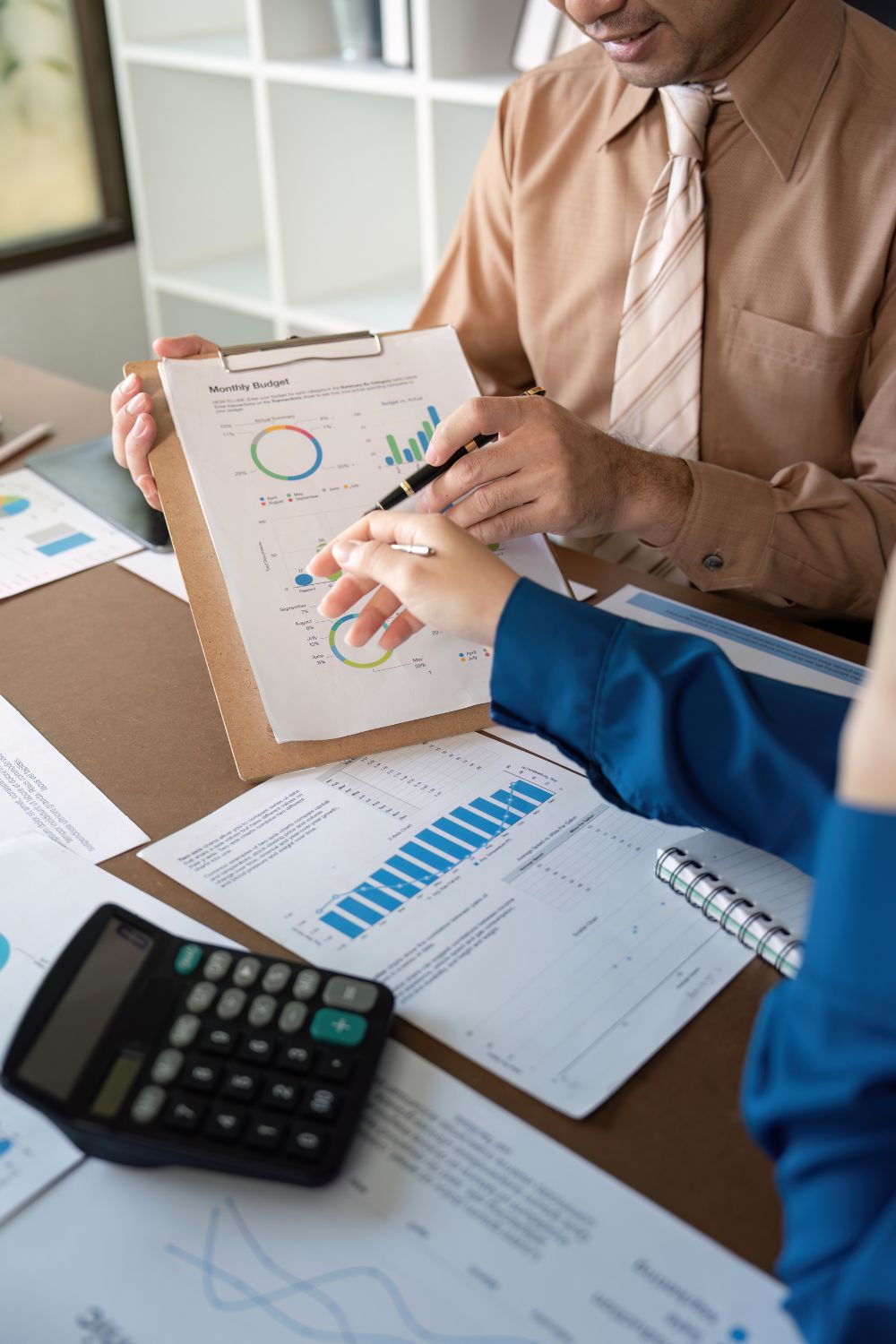 Team reviewing social media campaign 2025 metrics and financial charts on a clipboard.