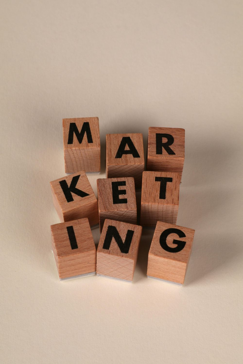 Wooden blocks arranged to spell the word marketing on a neutral background.