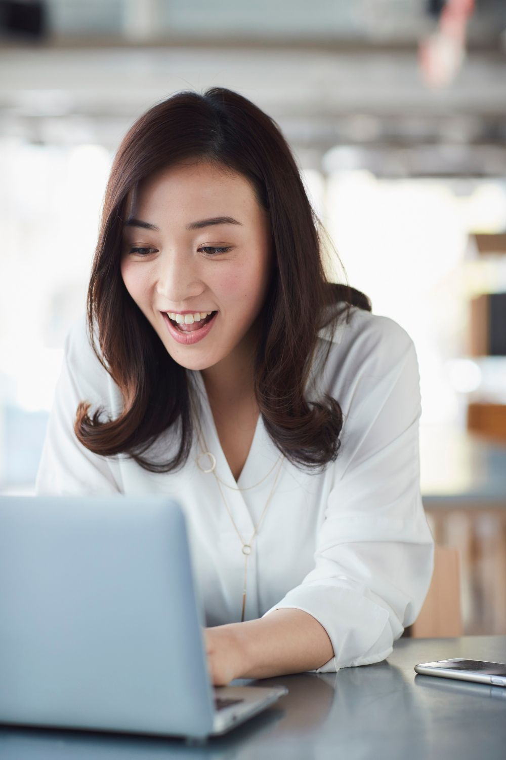 Woman smiling while working on a laptop during a social media strategy session.