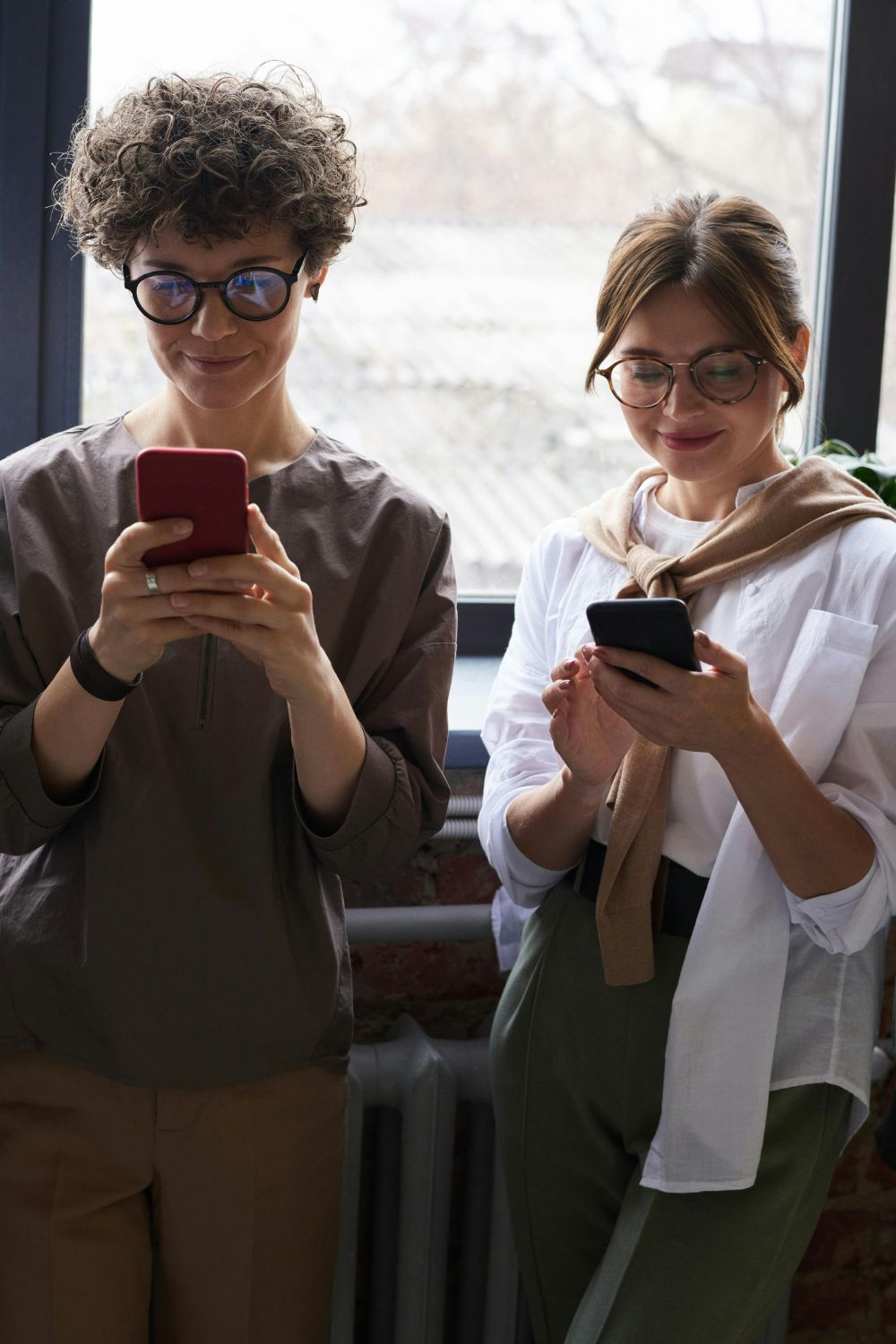 Two people using smartphones to manage social media apps and engage online