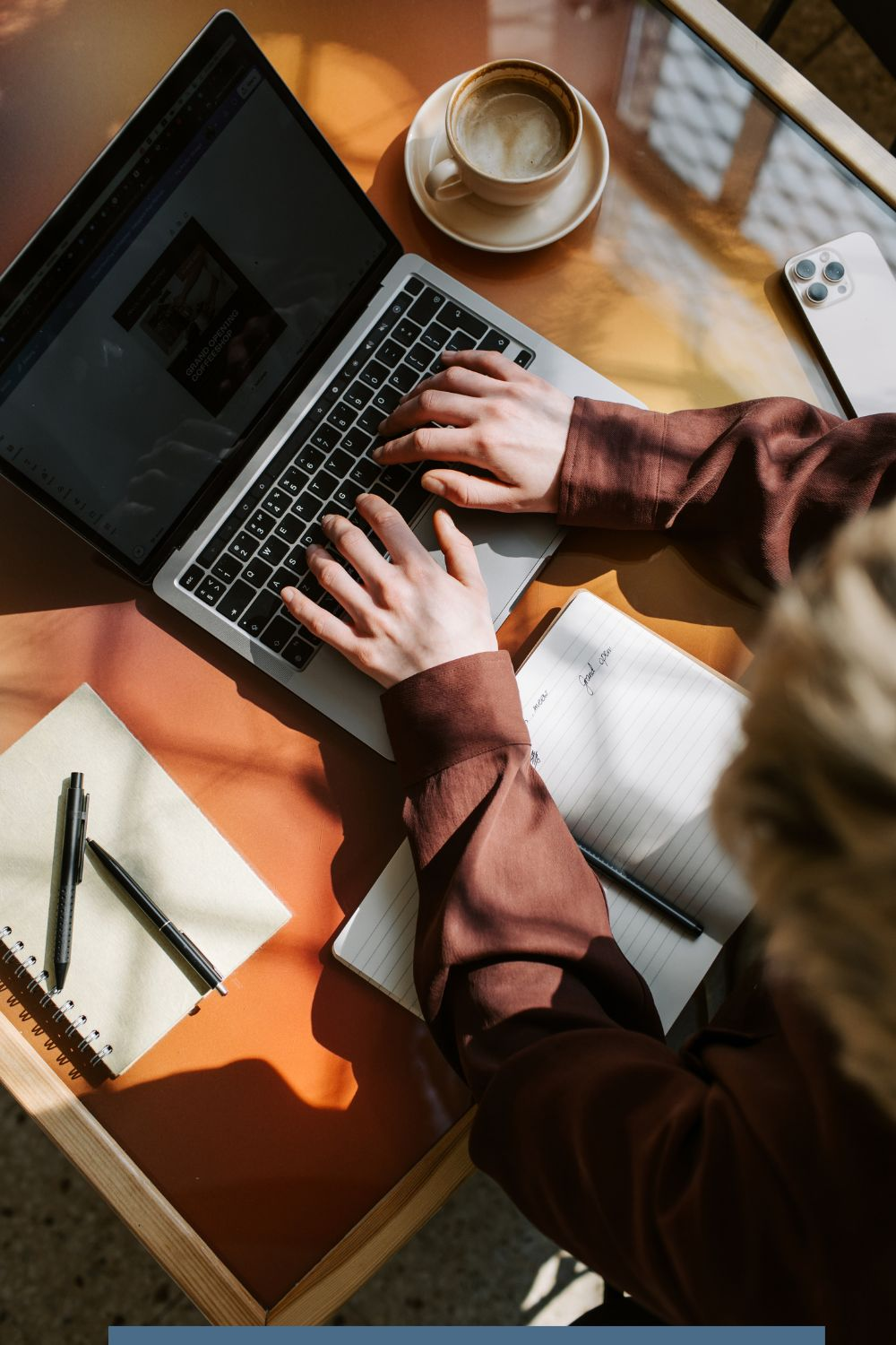 Person working on a laptop with a notebook and coffee cup while planning a social media strategy